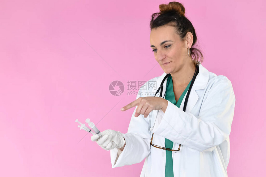微笑的女医生一方面持有三支不同的注射器图片