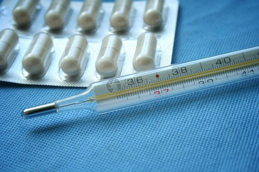 蓝色背景上的片剂药丸和水银温度计流感冒的概念医疗保健概念药图片