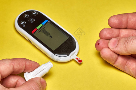 一个糖尿病人检查他的血糖亲近男人的双手用柳叶刀和水晶仪在家中图片