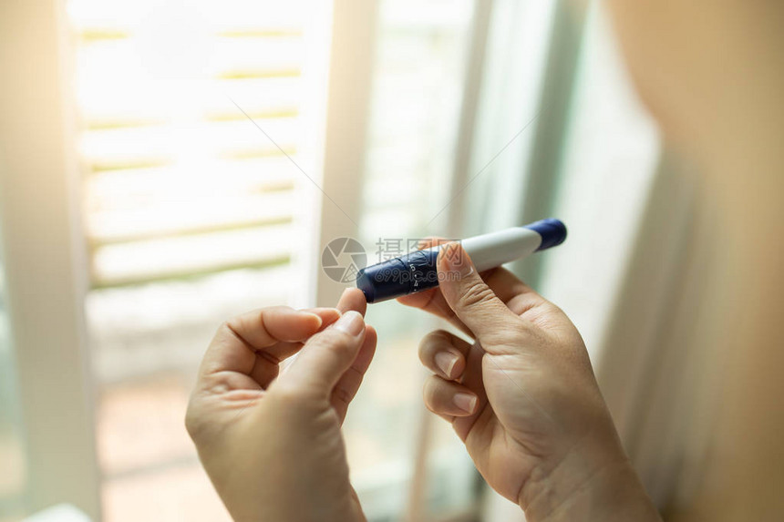 用手指上的柳叶刀在早上用血糖仪检查血糖水平的女人手的特写用作医学糖尿病血糖保图片