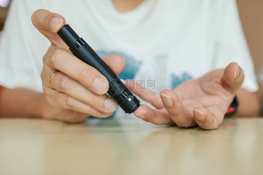 用手指上的柳叶刀用血糖仪检查血糖水平的人手的特写用作医学糖尿病血糖保图片