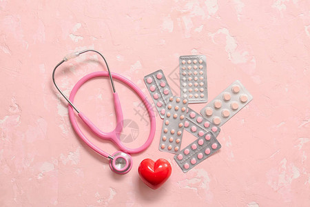 彩色背景上的听诊器心脏和药丸心脏病学概念图片