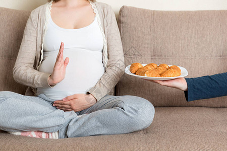 孕妇在沙发上放松的特写对羊角面包做停止手势准妈拒绝吃糕点怀孕期图片