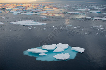 从海上看北冰洋北部融化的浮冰中漂流夕阳在海面上投下橙色的光芒气候危机紧急情背景图片