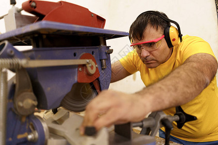 木匠在其木工车间用圆锯砍掉一块木头作为家具图片