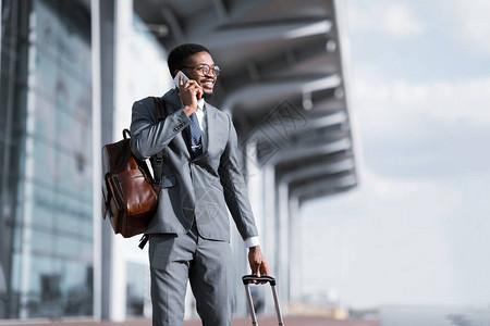 旅行商人非洲男子在机场电话交谈和随行李图片