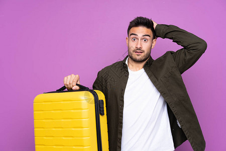 年轻英俊男子在度假时带着旅行李箱和惊喜与世隔图片