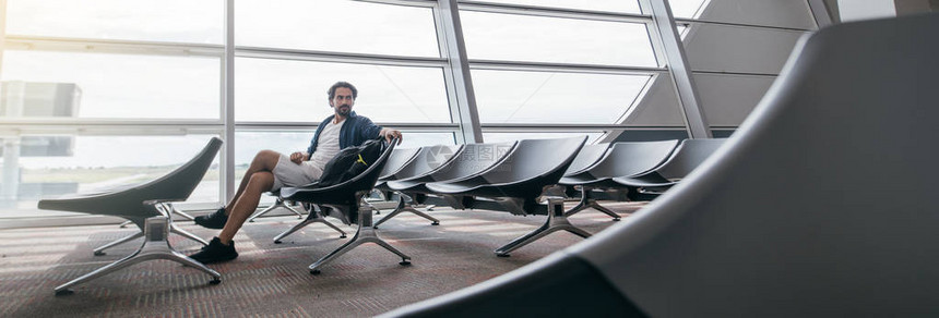 一名男子坐在机场大门口的候机室里图片