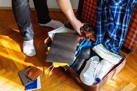 旅行概念男人把东西放在手提箱里装着衣图片