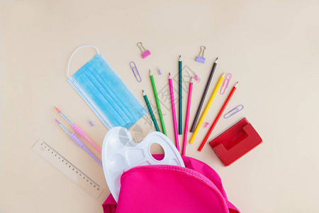 一个防护医用口罩和学校和办公用品从粉红色的背包中散落图片