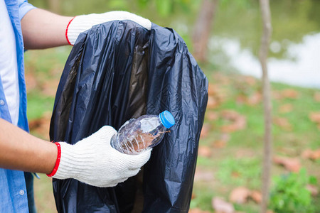年轻志工将塑料瓶放在垃圾袋清洁区图片