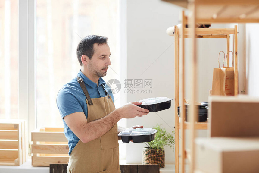 成人男子在食品交付服务工作时在书架上装着堆叠塑料包装的围裙复制空图片