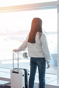 机场候机楼离境大厅区年轻女乘客带行李的机场旅客生活方式图片