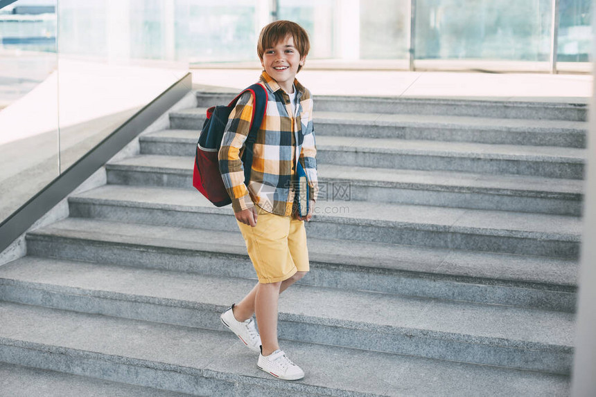 带着背包的快乐男孩和一本书上学图片