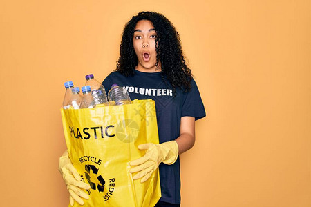 年轻的非洲裔美国妇女做志愿回收塑料瓶的手提袋图片