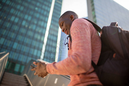 年轻非裔美国人一边看着城市手机在图片