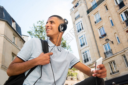 北部非洲男孩学生在城市用耳机和手机监听音乐的喜悦北非青图片