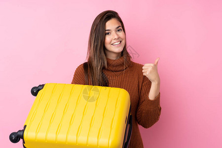 在度假时带着旅行手提箱和大拇指在与世隔绝的粉红背景上度背景图片