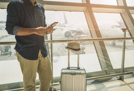 观光客正在机场从他们的智能手机上查看旅游节目图片
