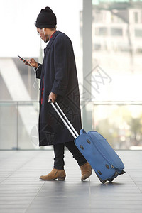 非洲旅行男子在车站用手机和手提箱行走的全身图片