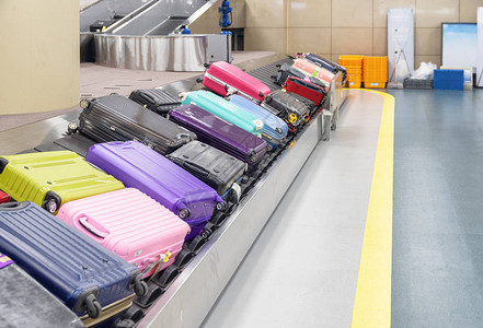 在机场客运终点站抵达区行李传送带上多彩色手提箱图片