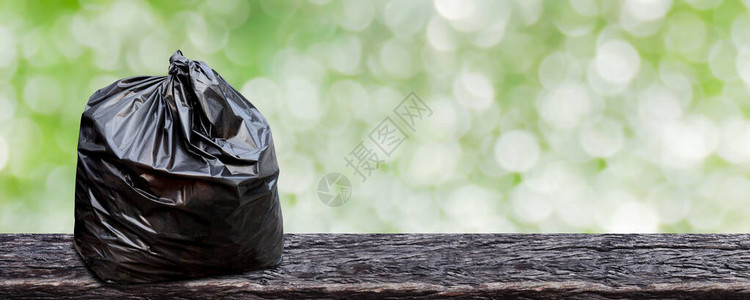 背景用木板上的塑料垃圾袋用于回收废物的垃圾袋包装木地板上的黑色塑料袋图片