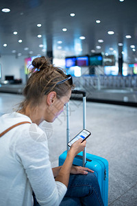 年轻女子带着行李在国际机场图片