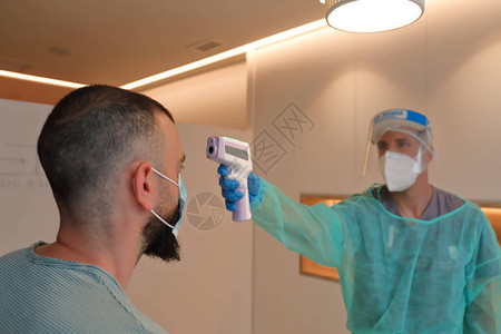 戴防护面罩的男医护人员用数字非接触式温度计图片