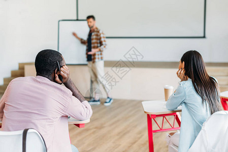 英俊的年轻老师在大学里为一群学生做演讲图片