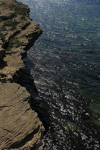 以闪亮的海面为背景的岩石海岸图片