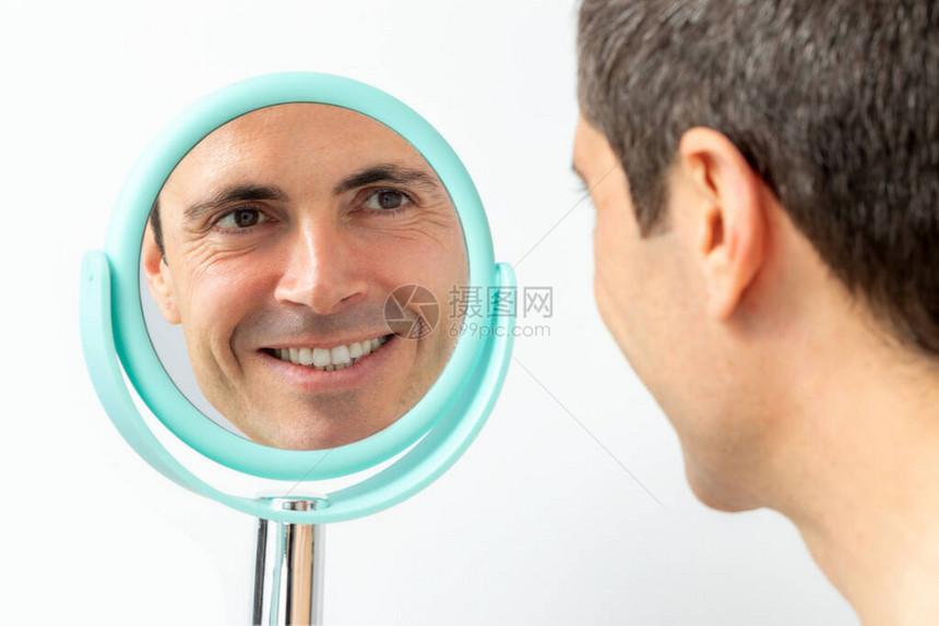 近距离的中年男子肖像在手镜中反射图片