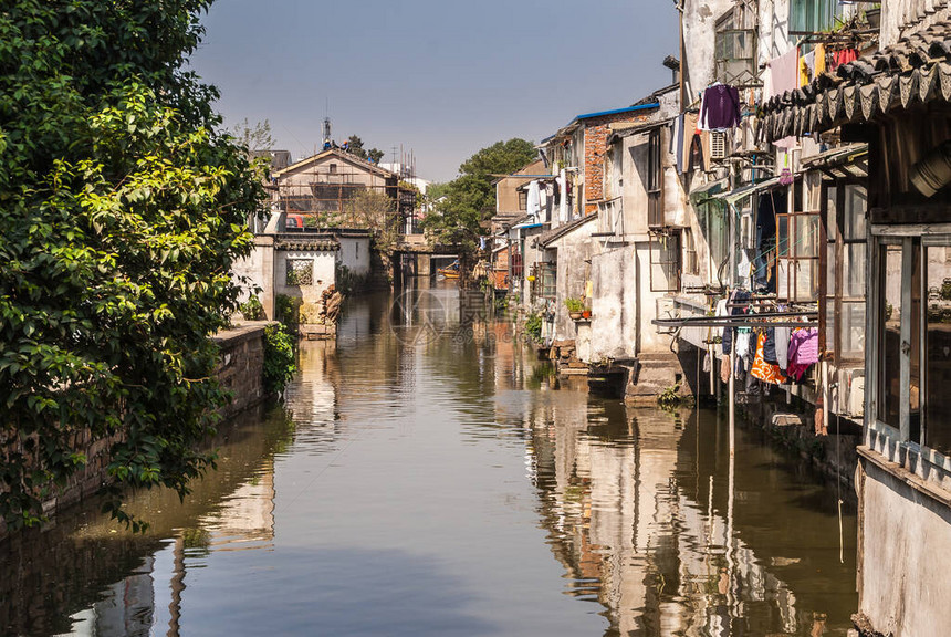 城市运河加棕色水反映了房屋沿水边的背面图片