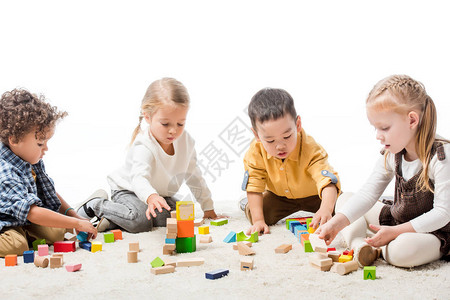 在地毯上用木砖块玩耍的多种族可爱儿童图片