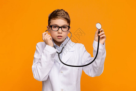身着医生制服的十几岁男孩持有听诊器橙图片