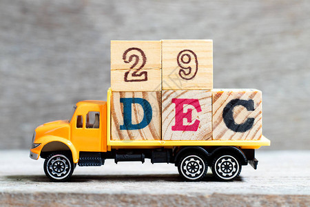 卡车在木材背景上持有字数为29Dec的字母块日图片