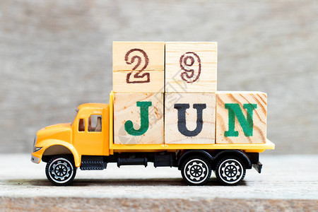 关于木材背景的卡车持有字29jun的字母块设想日期为图片