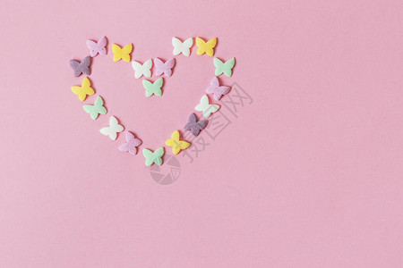 多色糕点多色薄粉喷洒和滴虫以心脏的形状在粉红色背景上布置甜图片