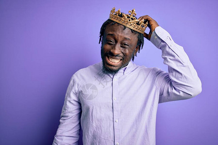 年轻的非洲裔美国人在孤立的紫色背景下戴着国王的金冠图片