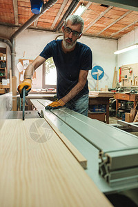 木匠将一块木头推入锯切机从机器角度看图片