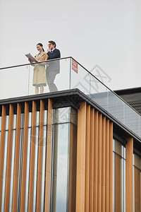 两个商业人员在办公楼顶上站着图片