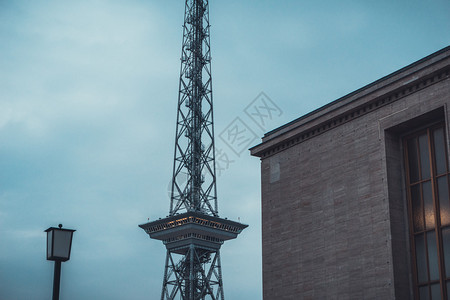 在黑暗天空下建筑旁边的单一大型广播传输天线塔和灯台图片