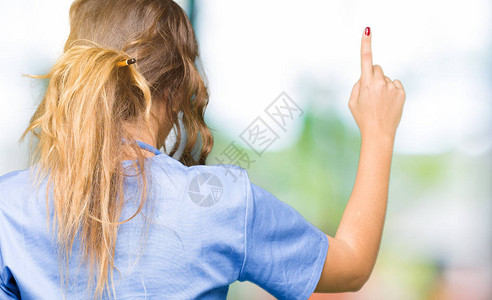 身穿医疗制服的年轻成年女医生用手指向图片