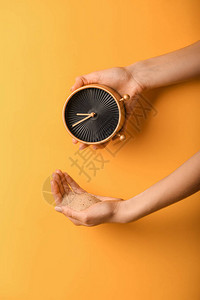 彩色背景上带时钟和沙子的女手时间管理概念背景图片
