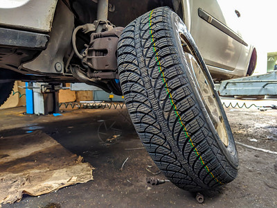 橡胶轮胎放在一辆没有车轮的汽车旁边图片