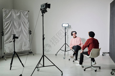 两位穿便装的年轻男流浪者坐在工作室和互动中的椅子上背景图片
