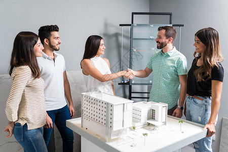 商业伙伴通过建筑模型与工程师在会议上握手图片