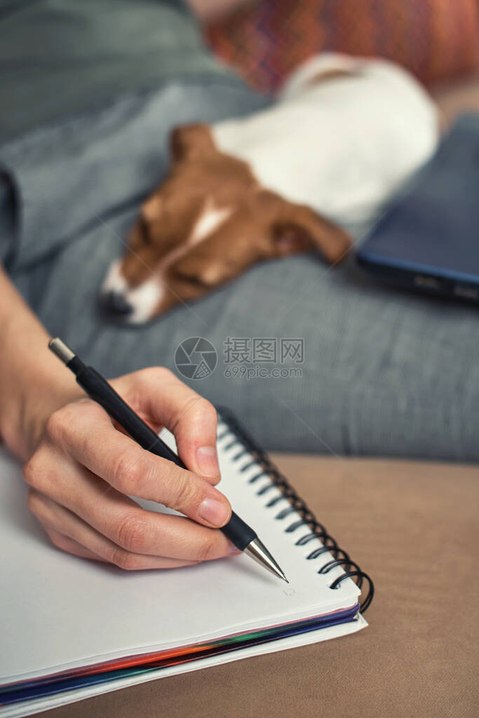 女人用笔记本和她的杰克鲁塞尔特瑞尔小狗一起写计划图片
