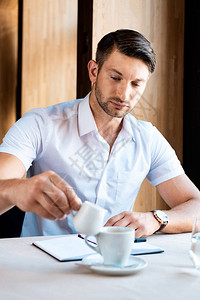 在咖啡厅咖啡中有专心的肌肉人将奶图片