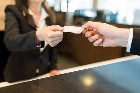 在酒店前台向商业专人员提供贺卡钥匙的办事员中流图片