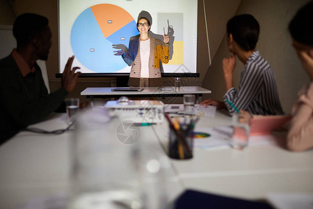身穿夹克正面自信的女金融分析师站在投影仪前背景图片